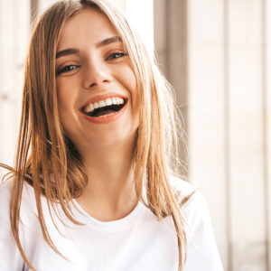 Blonde vrouw in een wit shirt geniet van stralende tanden door tanden bleken